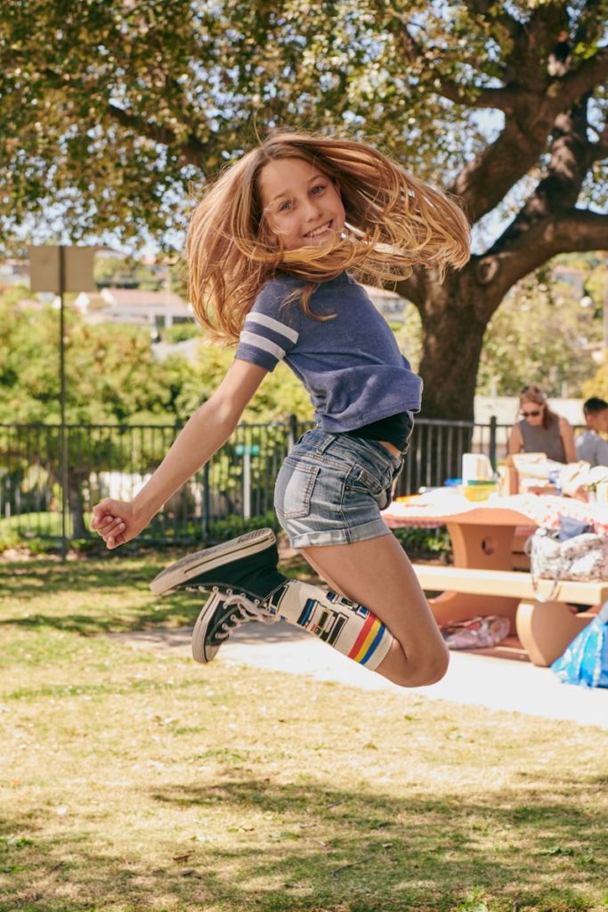 a girl jumping in the air with a skateboard